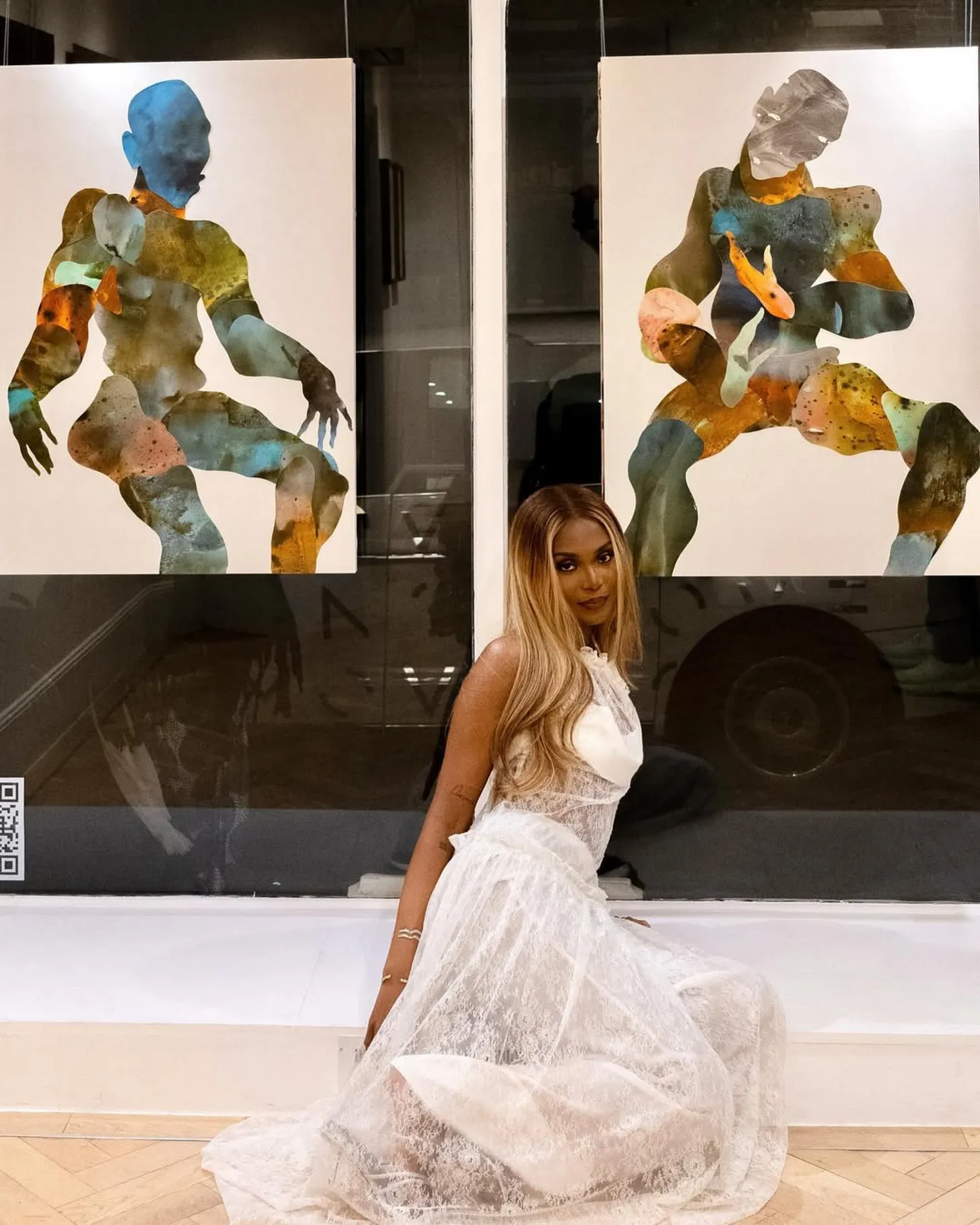 A minimalist art gallery space featuring a contemporary African sculpture on a pedestal with curated wall art.